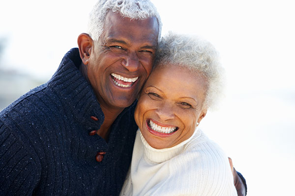 Two Dental Patients Smiling With Implant Supported Dentures