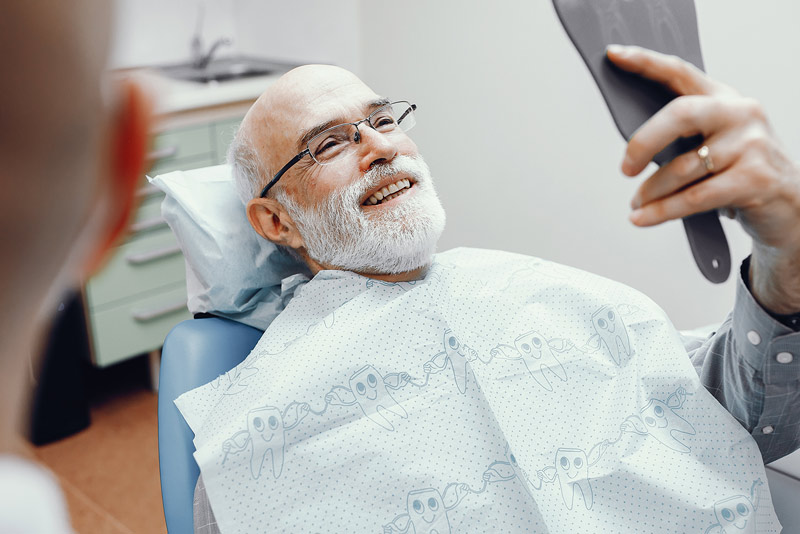 An image of an older man sitting in a dentist chair and smiling.